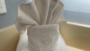 Une paire de serviettes blanches, soigneusement pliées, est posée sur une surface beige.
