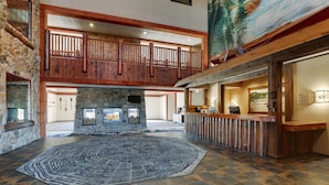 A spacious lobby with a stone fireplace, a wooden reception desk, and a large rug.