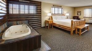 A cabin-style bedroom with a large bed, a wooden bench, a sink, and a window with blinds.