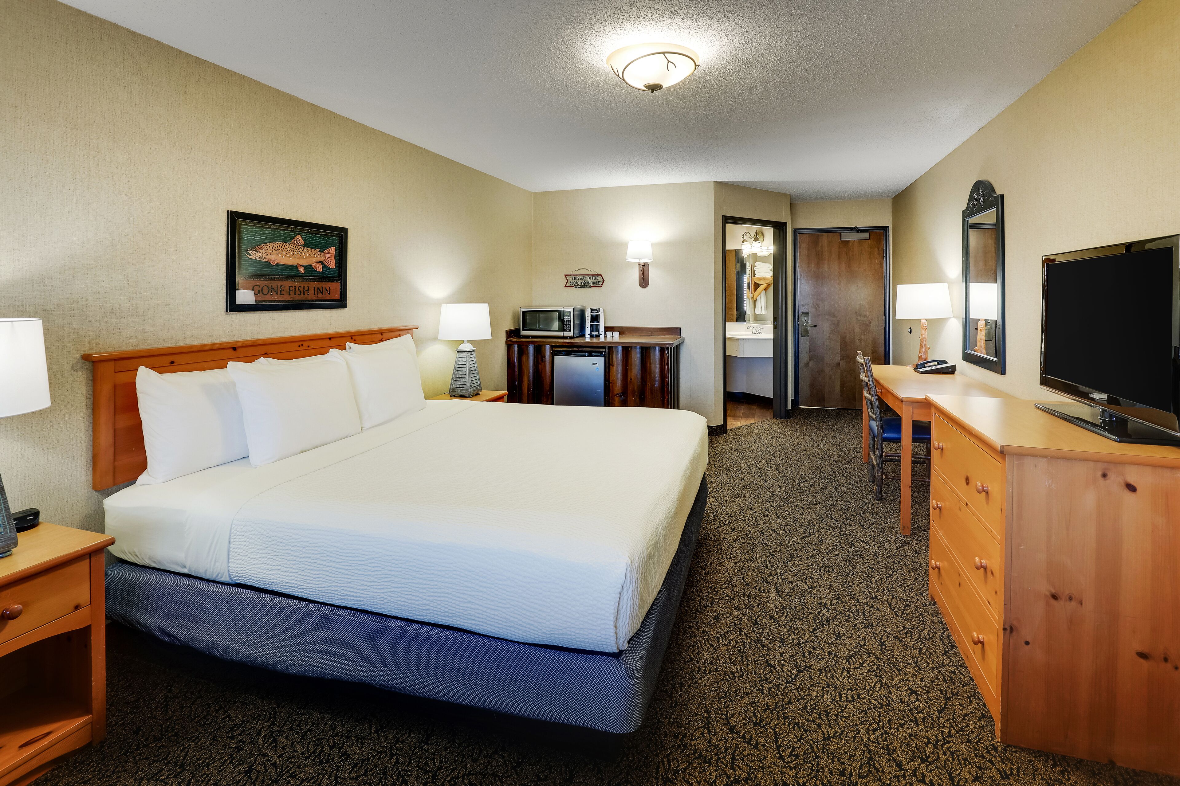 A hotel room with a large bed, a desk with a computer, a television, and a microwave.