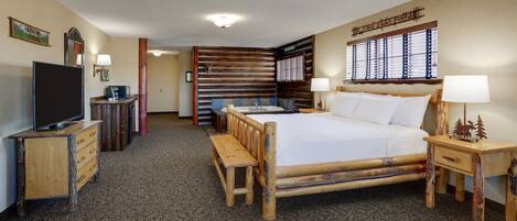 A room with a large bed, wooden furniture, a television, and a window with blinds.