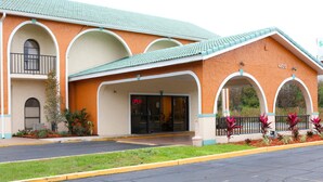 A building with a green roof, arched windows, and a sign indicating it is open. - Shining Light Inn & Suites (Kissimmee)