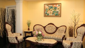 A room with a sofa set, two armchairs, a coffee table, and a floral arrangement. - Shining Light Inn & Suites (Kissimmee)