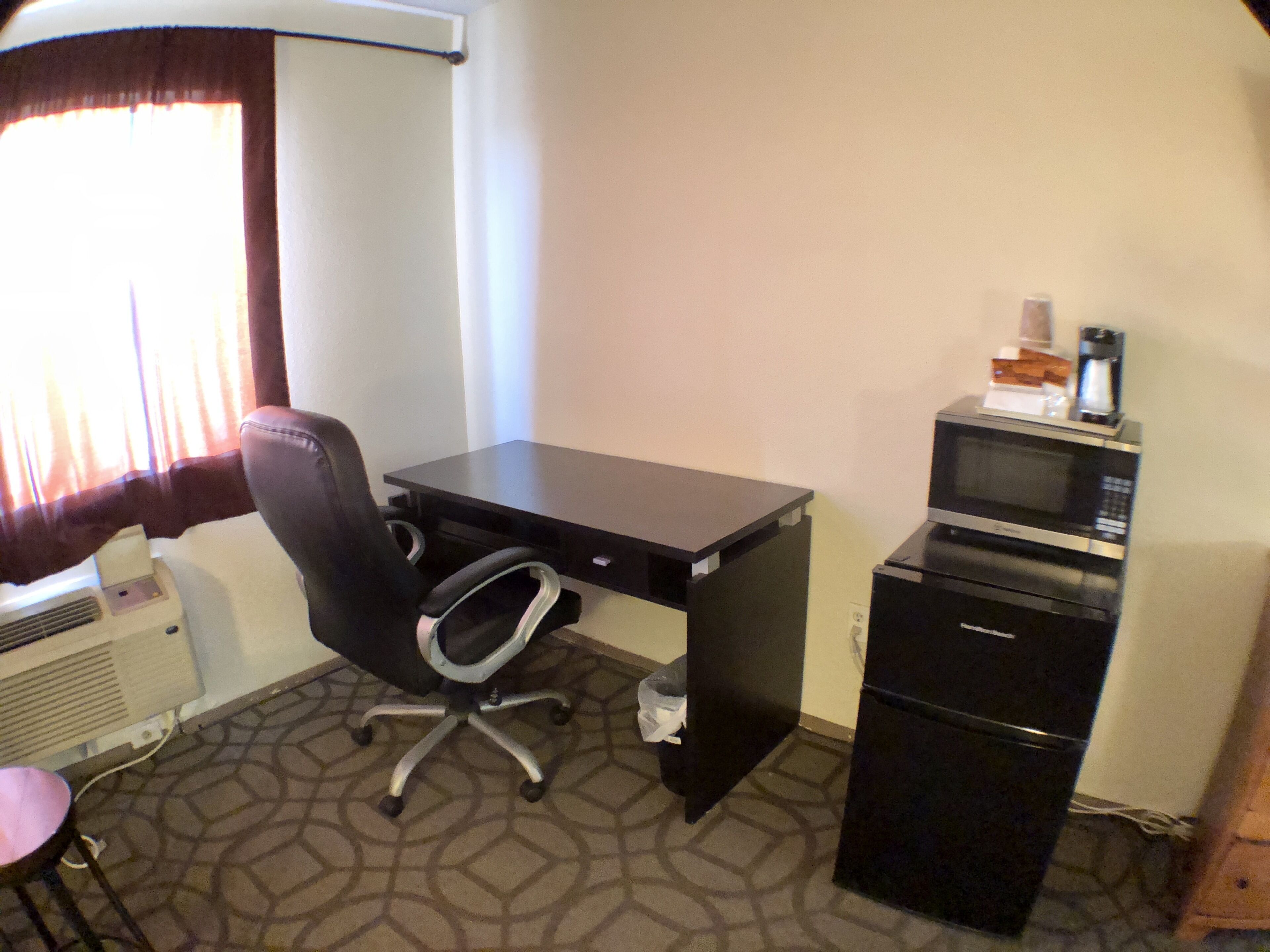 A small office with a desk, chair, microwave, and filing cabinet.