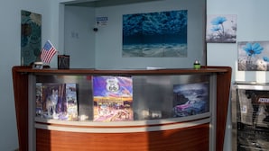 A reception desk with a wooden finish, a framed American flag, and a 'NOTICE' sign on the wall. - Tower 64 Motel & RV Park (Trinidad)