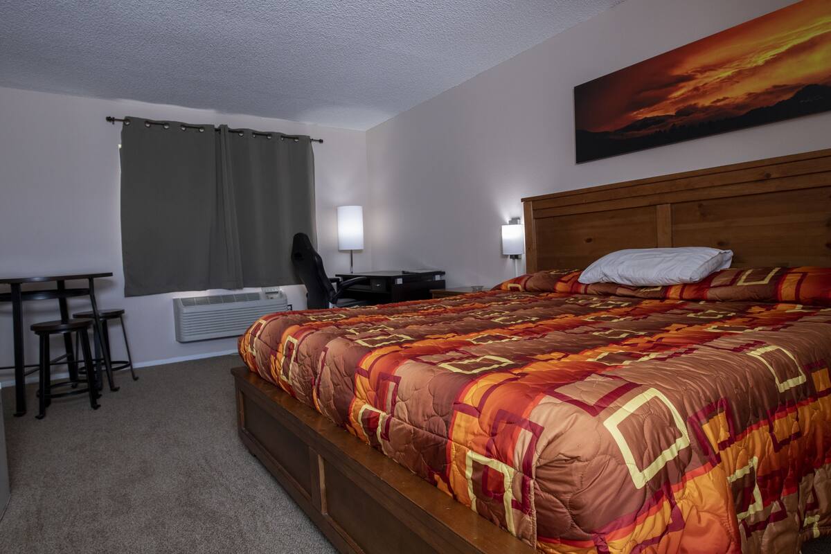 A bedroom with a large bed, a desk, and a chair.