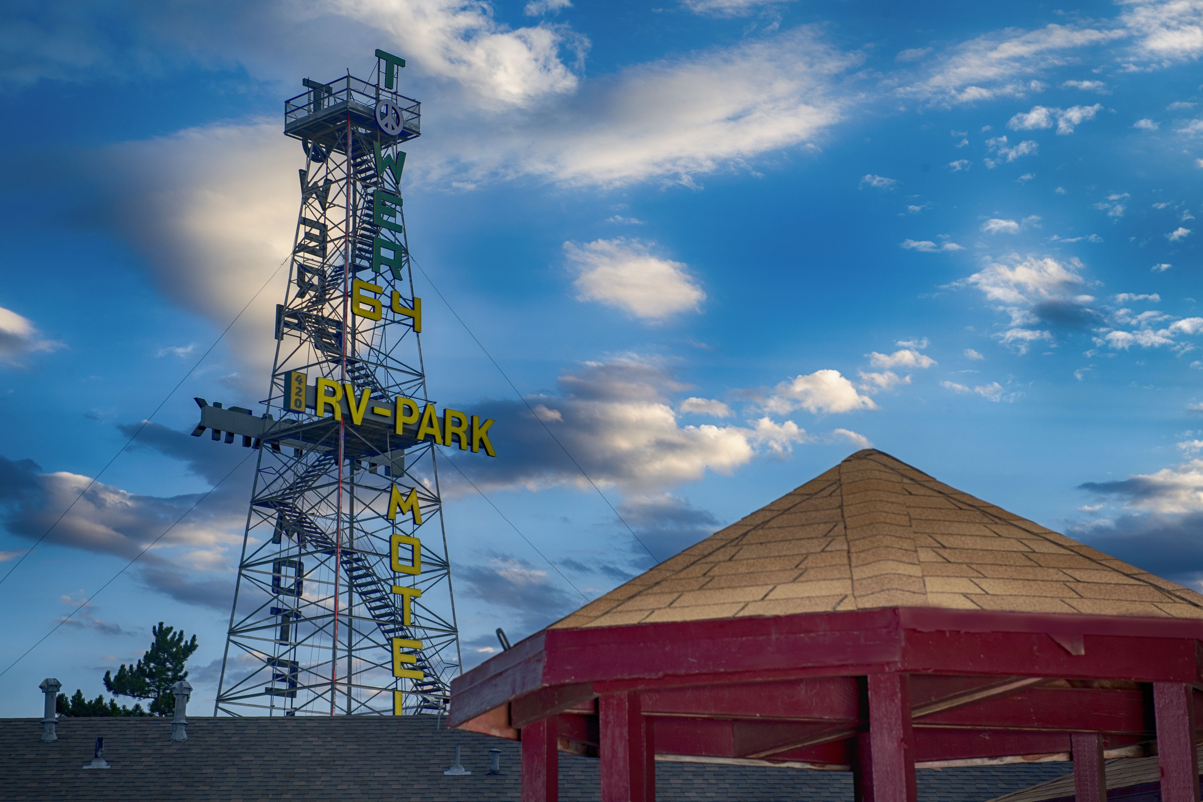 Una estructura alta con un letrero que dice "RV-PARK" y un edificio de techo rojo cercano.