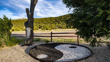 Un jardín zen con una roca grande, grava y una valla de madera.
