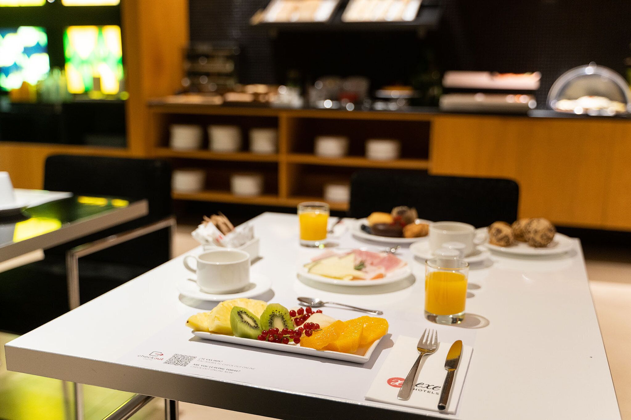 A breakfast table with a variety of food items, including fruits, pastries, and beverages.