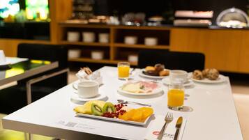 A breakfast table with a variety of food items, including fruits, pastries, and beverages.