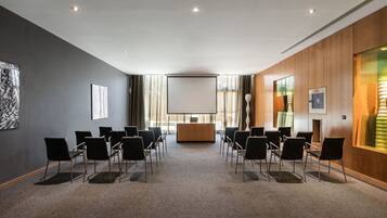 A conference room with a long table, chairs, a podium, and a large screen.