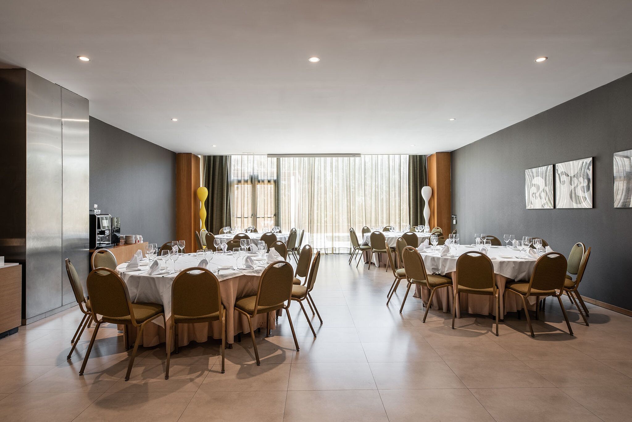 Un comedor amplio con varias mesas redondas dispuestas para comer, equipado con sillas y vajilla.