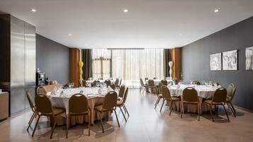 Un comedor amplio con varias mesas redondas dispuestas para comer, equipado con sillas y vajilla.