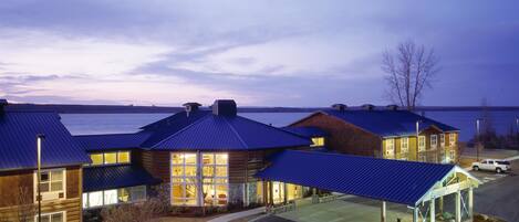 A hotel with multiple buildings, a covered parking area, and a view of the water.