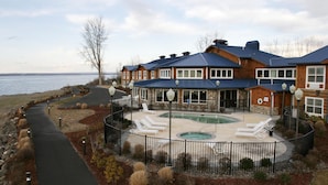 A resort with a pool, lounge chairs, and a view of the water. - River Lodge and Cabins (Boardman)