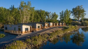 A row of cabins by a lake with a wooden deck and a paved path leading to them. - River Lodge and Cabins (Boardman)