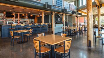A spacious restaurant with high ceilings, exposed wooden beams, and a variety of seating arrangements including tables and chairs.