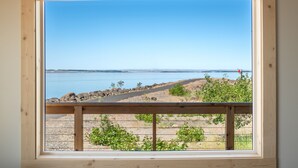 A window with a view of a beach and ocean. - River Lodge and Cabins (Boardman)