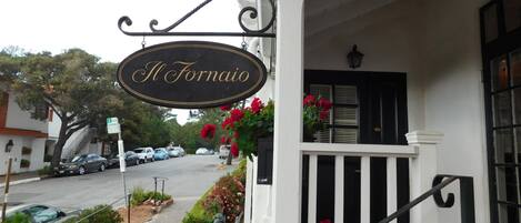 A building with a sign reading "Il Fornaio" and a white facade with black shutters.