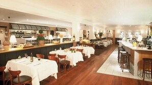 Un restaurant doté de plusieurs tables, d’un bar et d’une cuisine située à l’arrière.