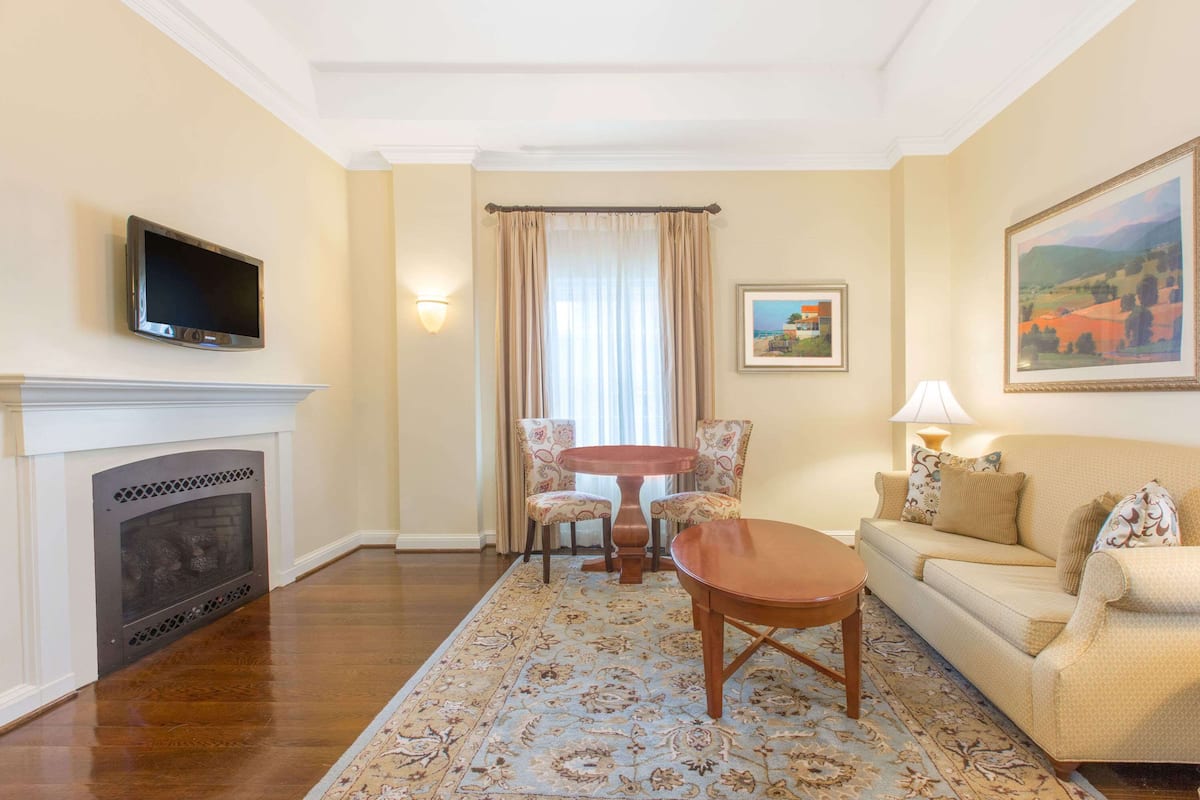 A living room with a fireplace, a television, a sofa, a coffee table, and a dining area with chairs and a table.