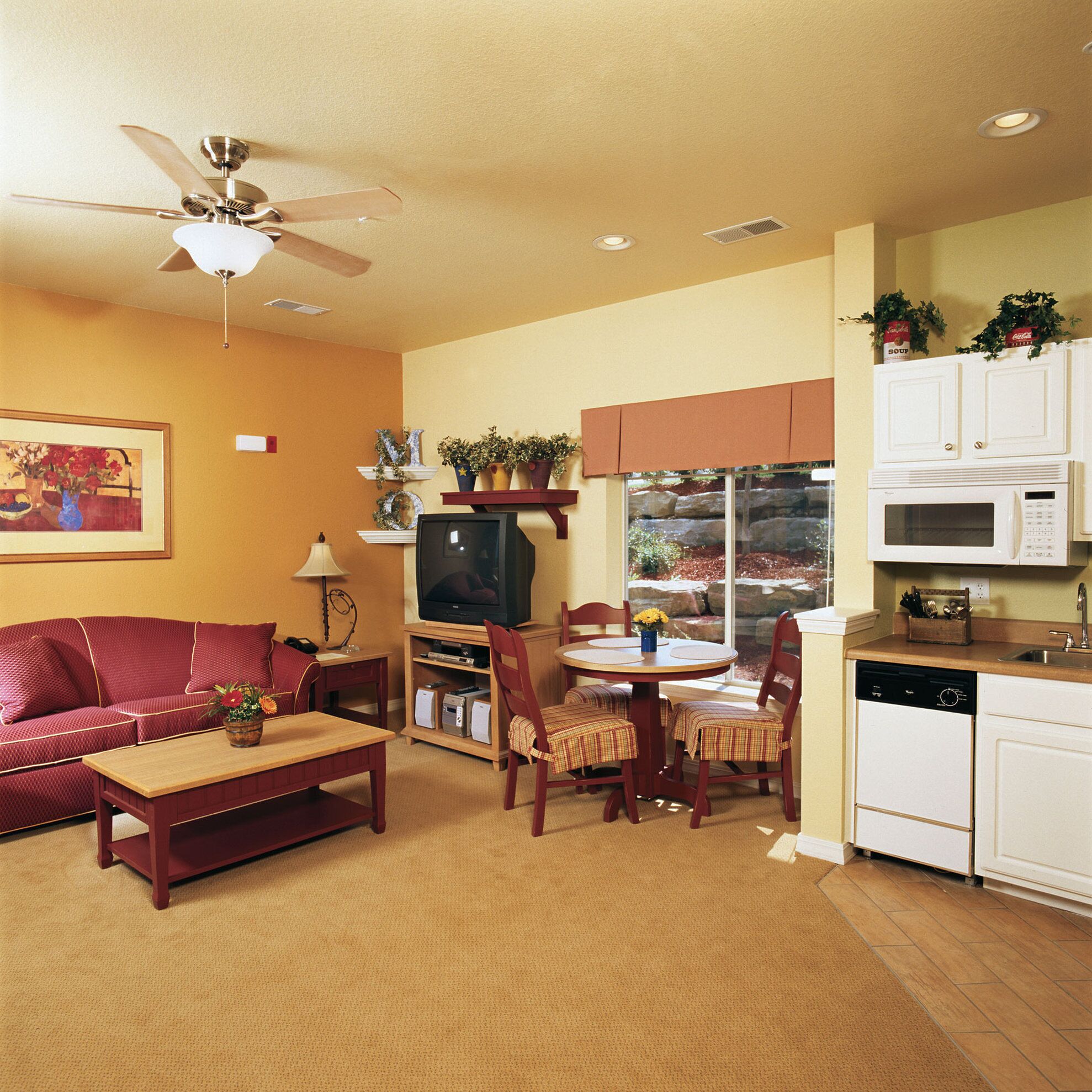 A living room with a sofa, coffee table, TV, and dining area with chairs and a table.