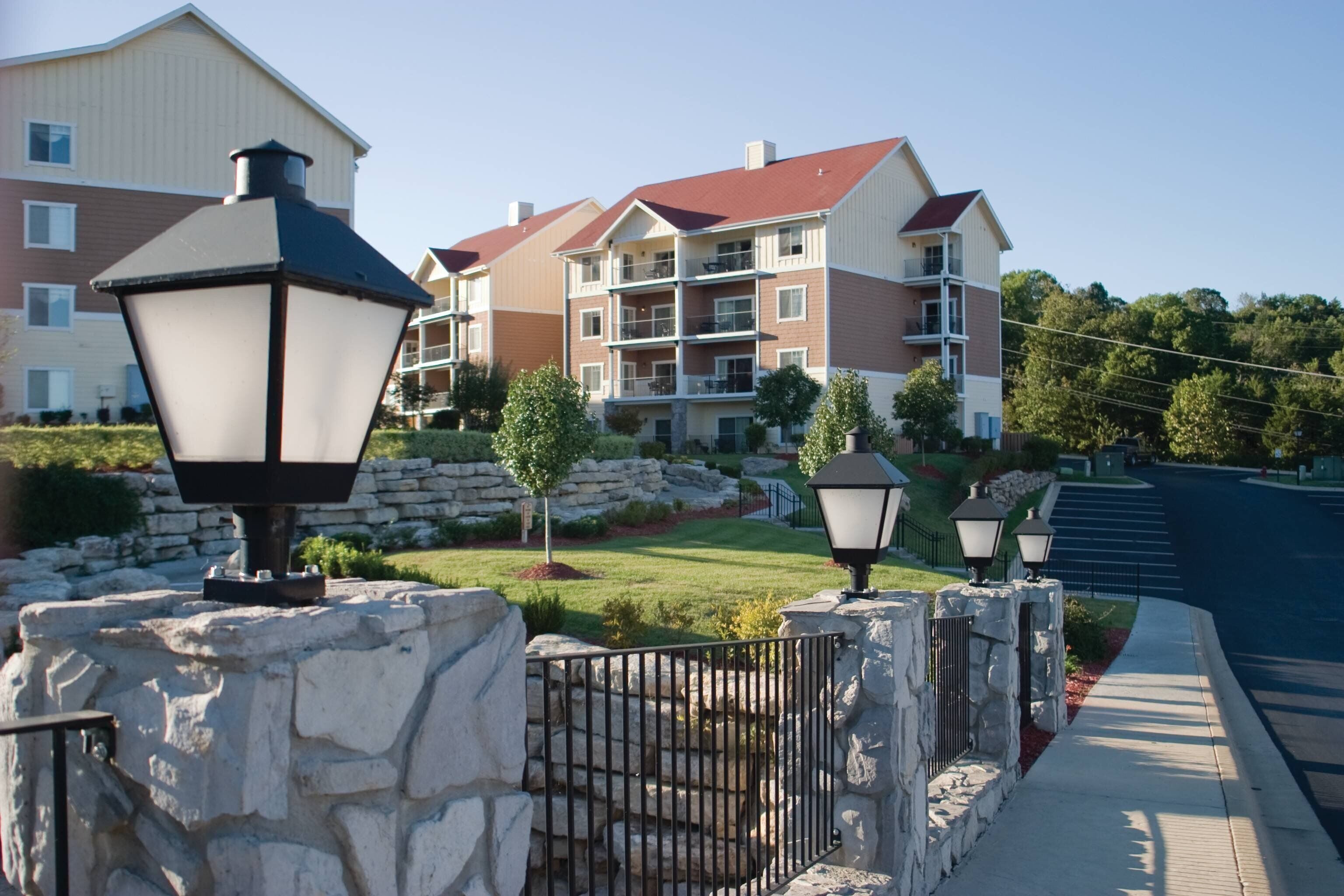 A residential building with multiple balconies, stone walls, and street lamps.