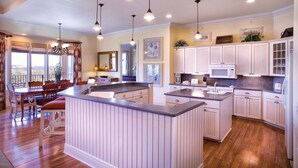 A spacious kitchen with a central island, white cabinetry, and pendant lighting.