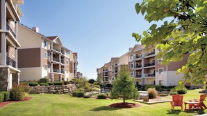A residential building with multiple balconies, a well-maintained lawn, and outdoor seating.