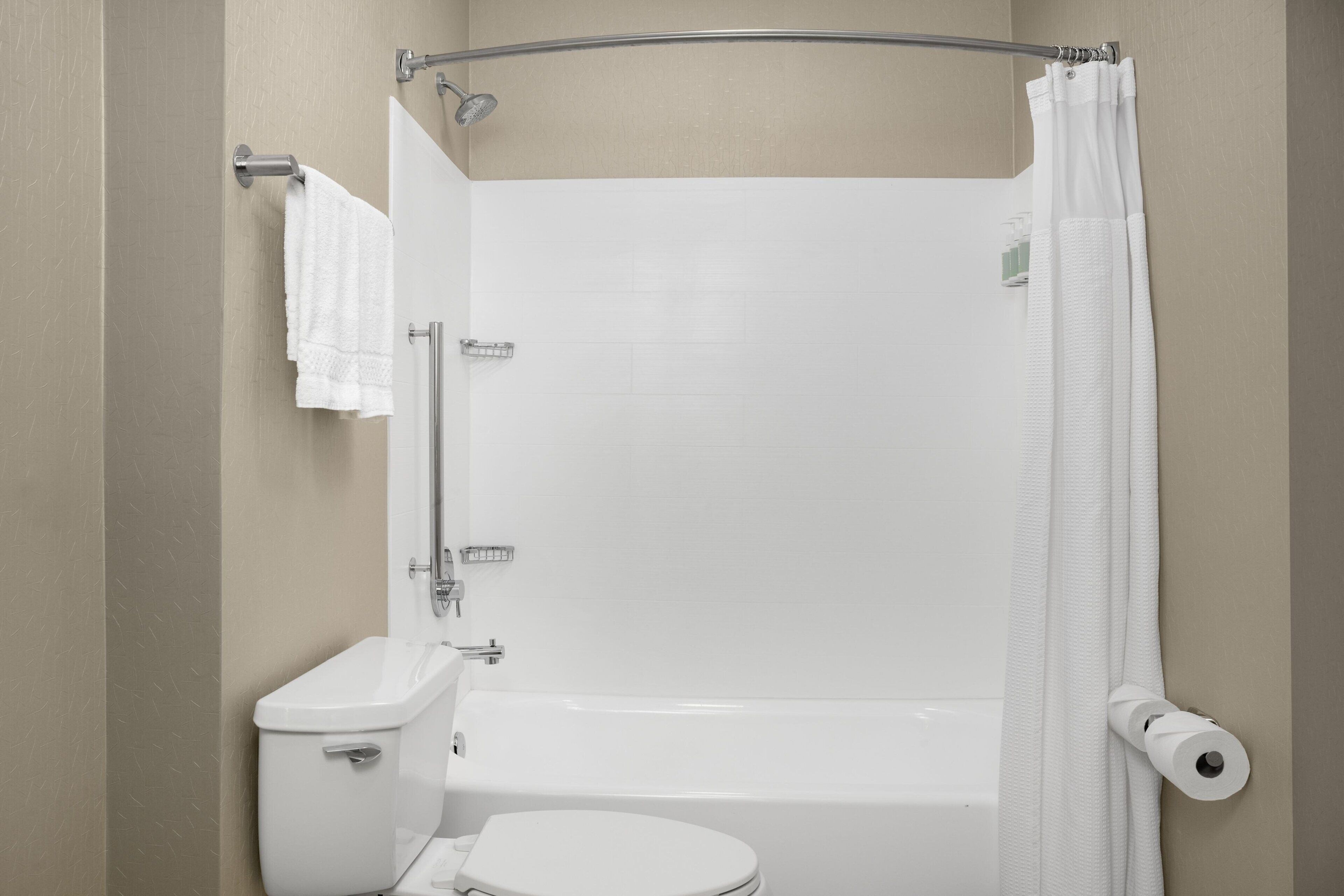 A bathroom with a toilet, bathtub, shower, and a towel rack.