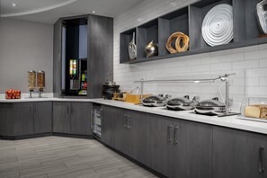 Una cocina moderna con gabinetes grises, una encimera blanca y varios electrodomésticos.