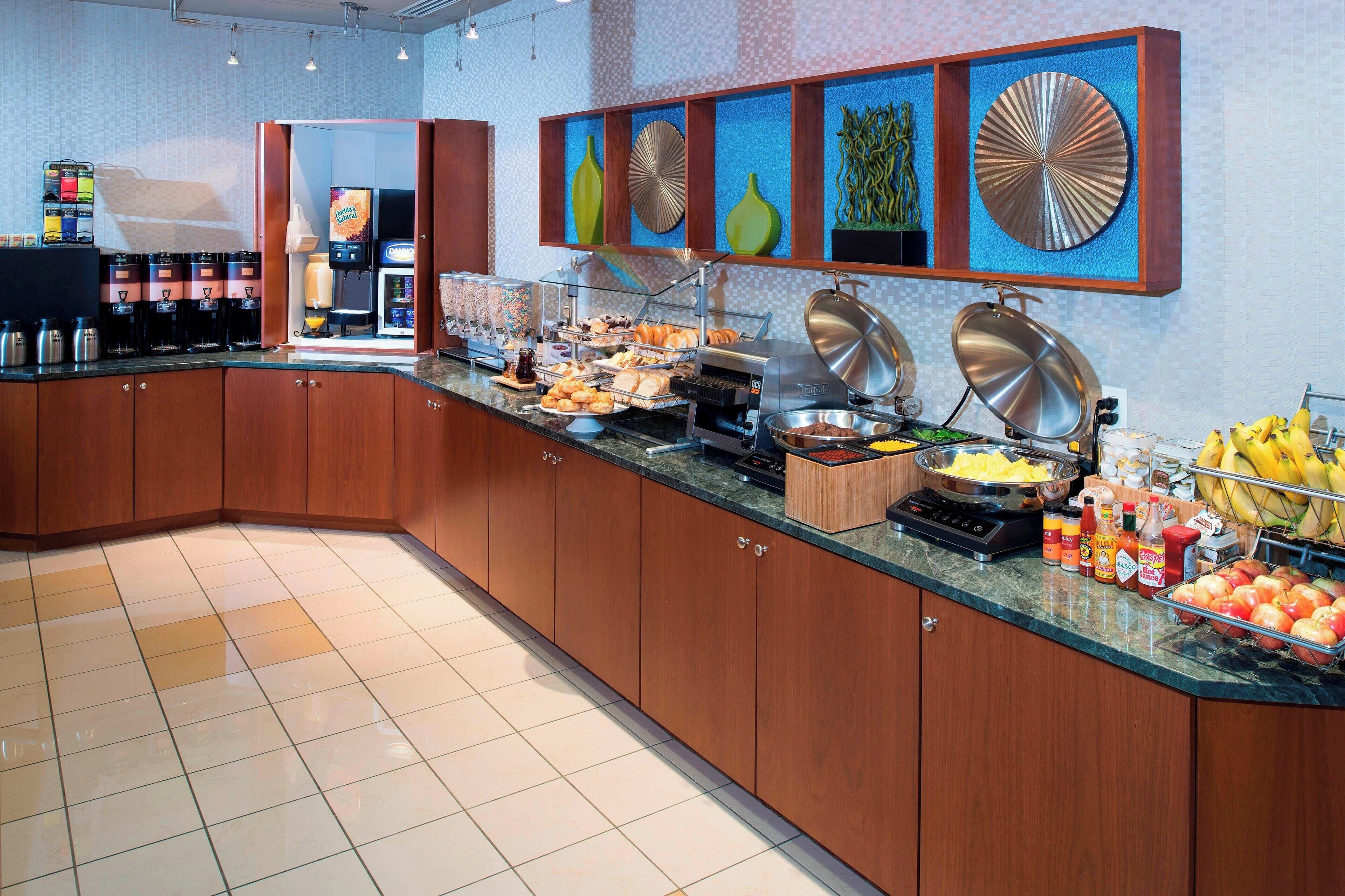 A buffet area with a variety of food items, a coffee station, and a fruit display.