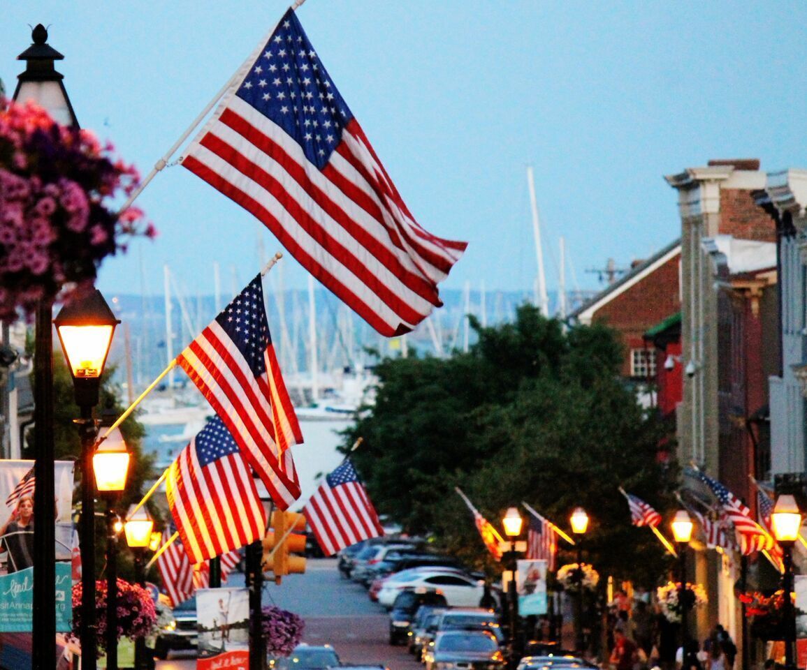 A street lined with American flags, street lamps, and parked cars.