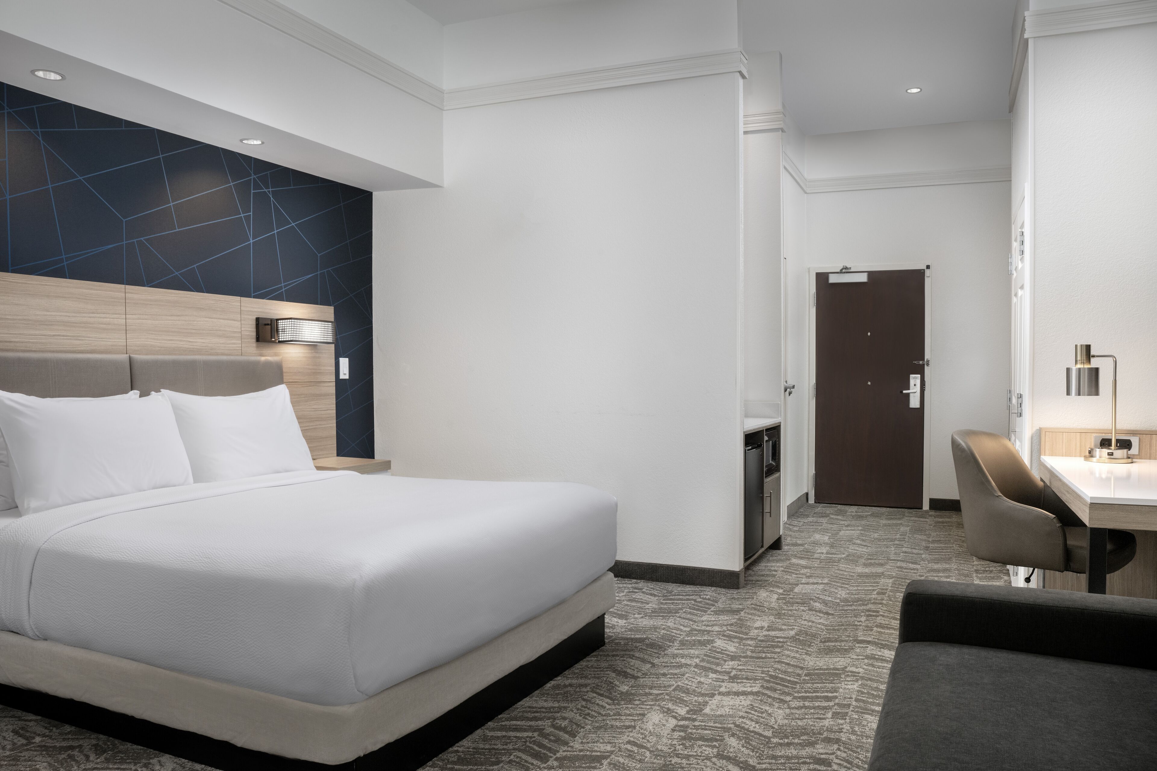 Una habitación de hotel moderna con una cama grande, un escritorio y una silla.