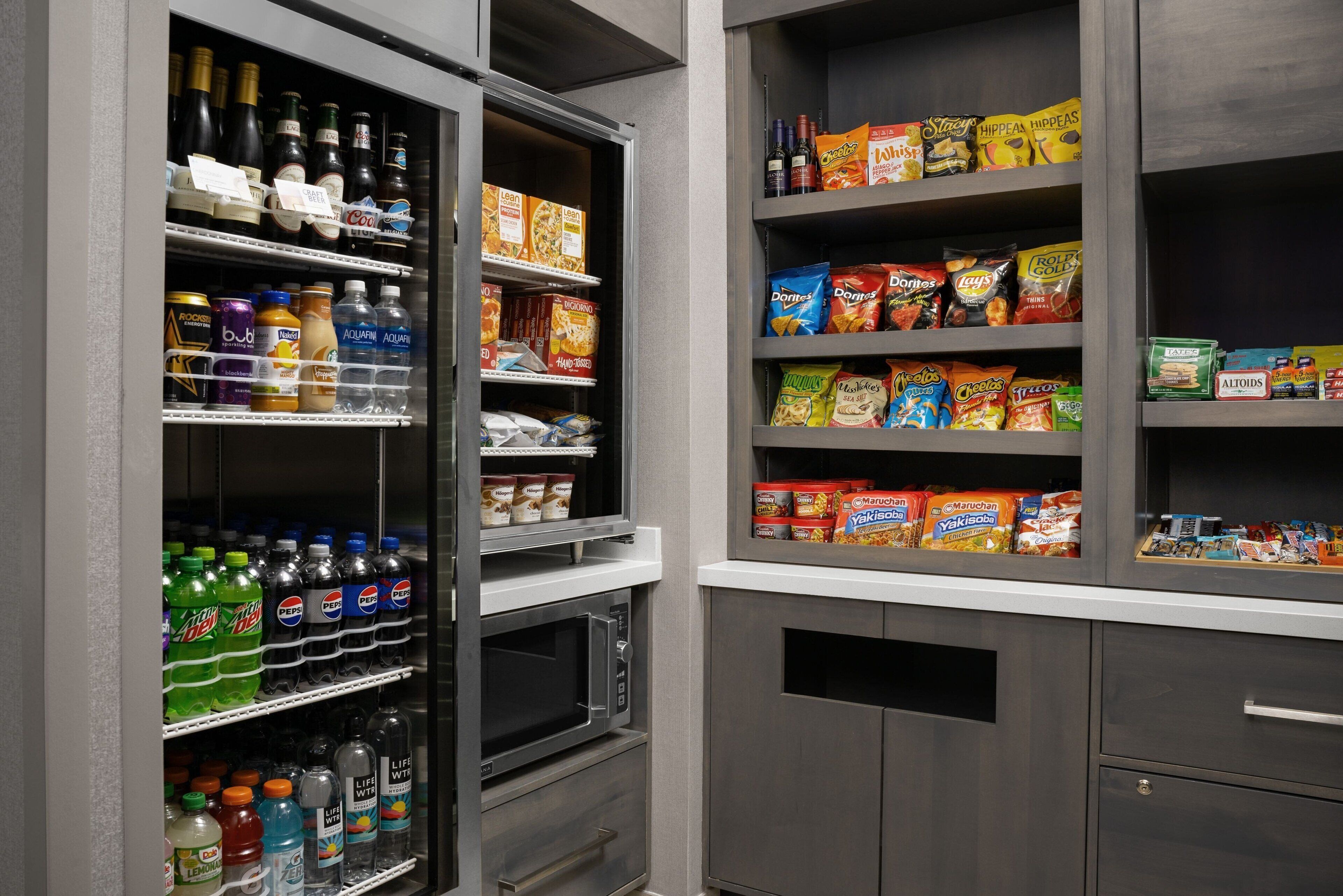 Una despensa bien organizada con estantes llenos de diversos alimentos, bebidas y aperitivos.
