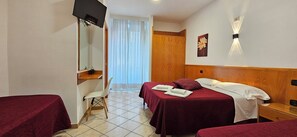 Una habitación de hotel con dos camas, un escritorio, una silla y un televisor.