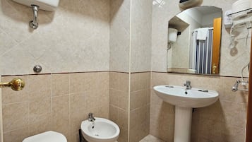 Une salle de bain équipée de toilettes, d’un bidet, d’un lavabo et d’un miroir.