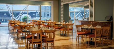 Un restaurante espacioso con múltiples mesas y sillas, amplias ventanas y una decoración interior moderna.