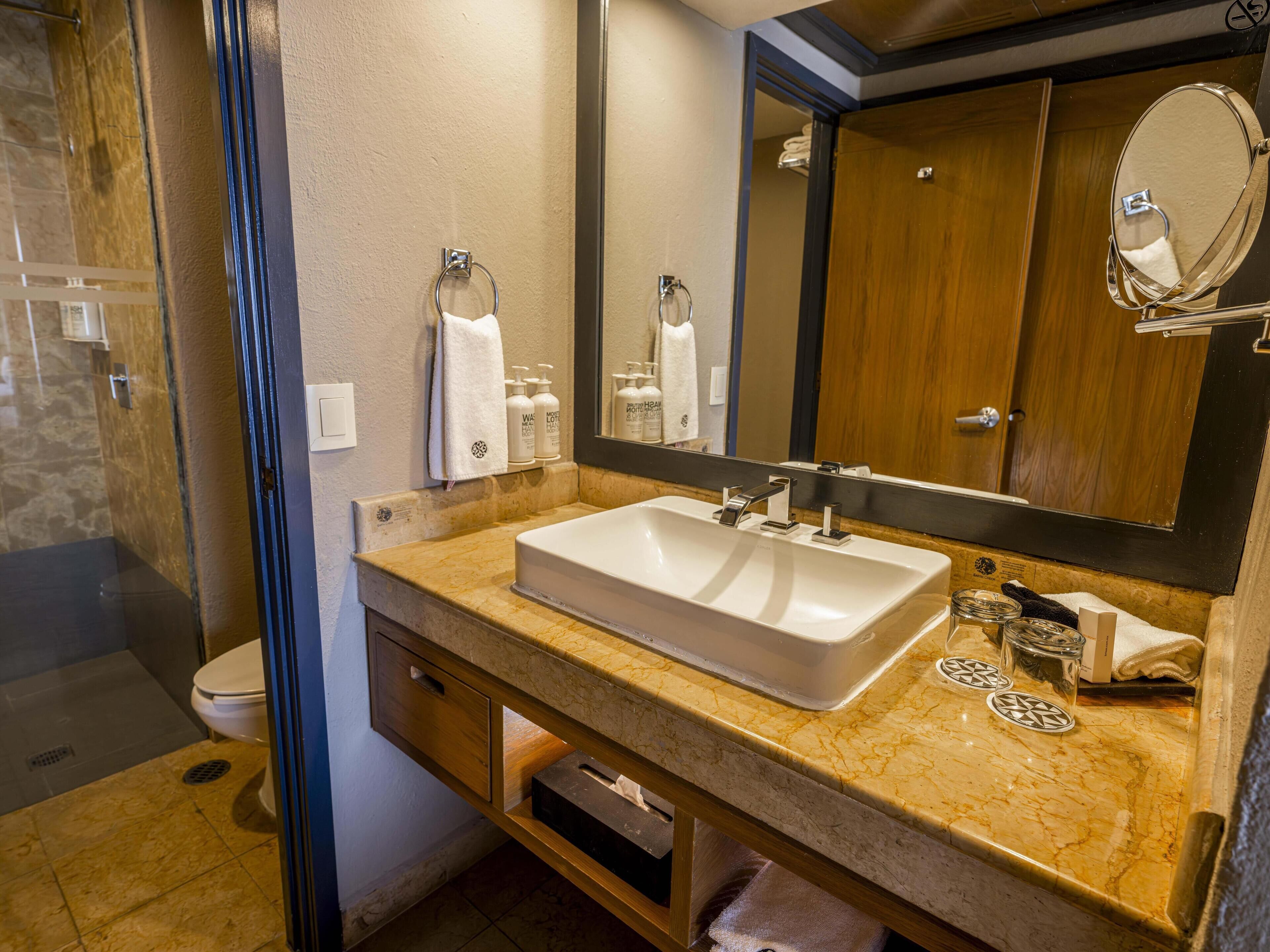A bathroom with a white sink, a mirror, and toiletries on the counter.