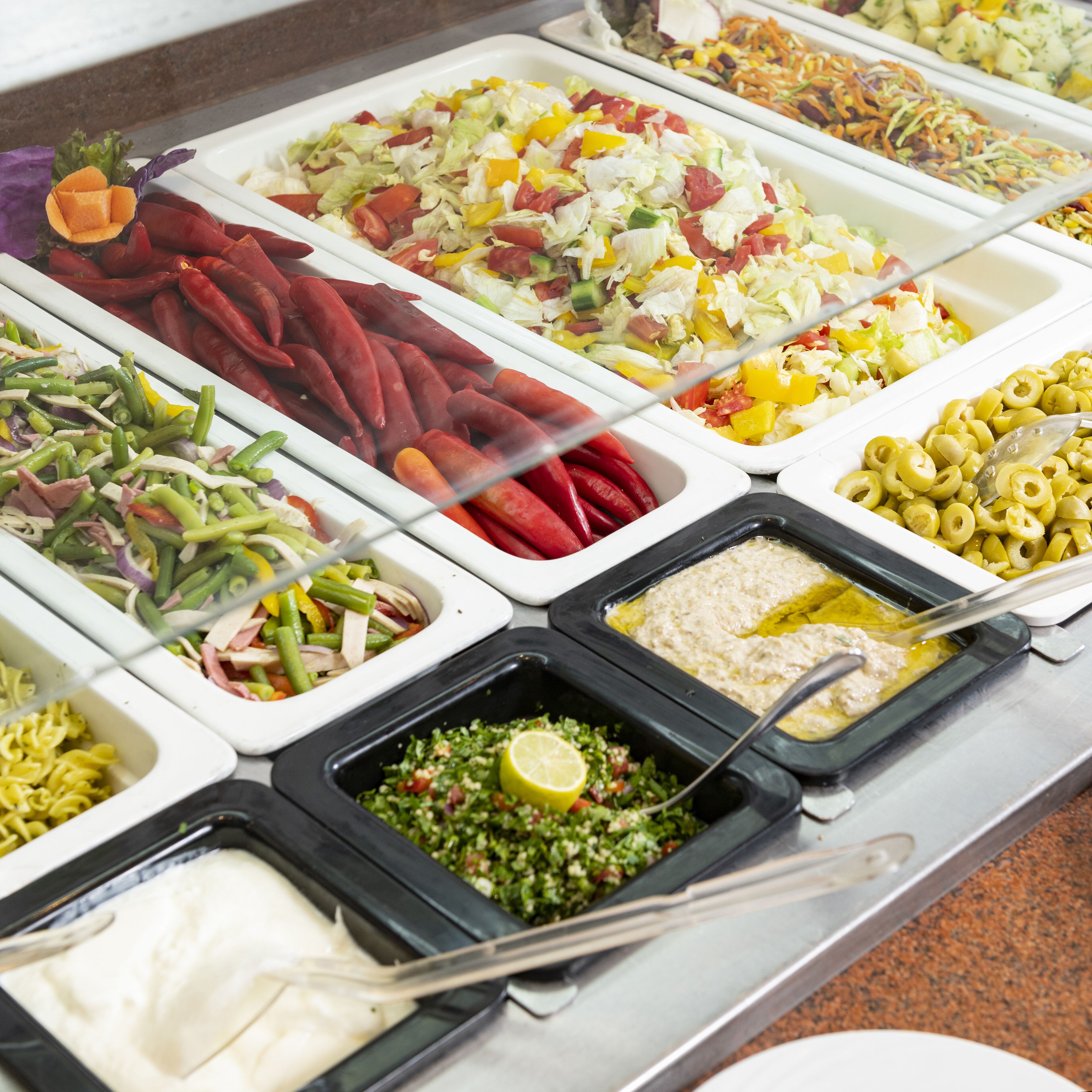 Un buffet proposant une variété de plats, notamment des salades, des pâtes et des sauces.