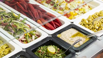 Un buffet proposant une variété de plats, notamment des salades, des pâtes et des sauces.