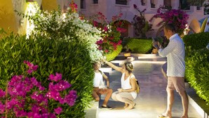 Un edificio con fachada rosa, varios balcones y un patio central con abundante vegetación y flores.