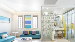 A modern living room with a sofa, a coffee table, and a glass partition with 'WELCOME' text. - The Purple Hotel by Ibiza Feeling - Adults only (Sant Antoni de Portmany)