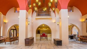Una hall con soffitti a volta, una zona salotto centrale con una poltrona rossa e lampadari a sospensione.