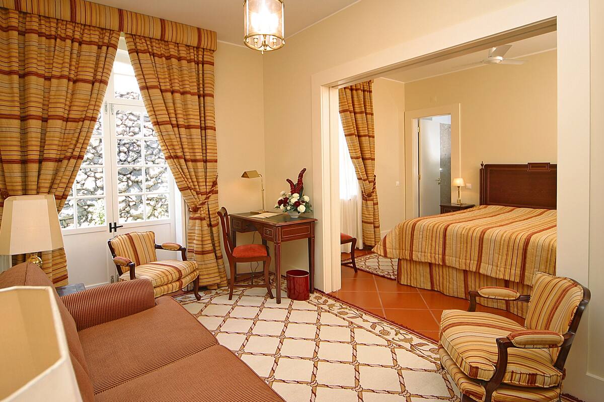 Une chambre d’hôtel avec un lit, deux chaises, une petite table et un bureau.