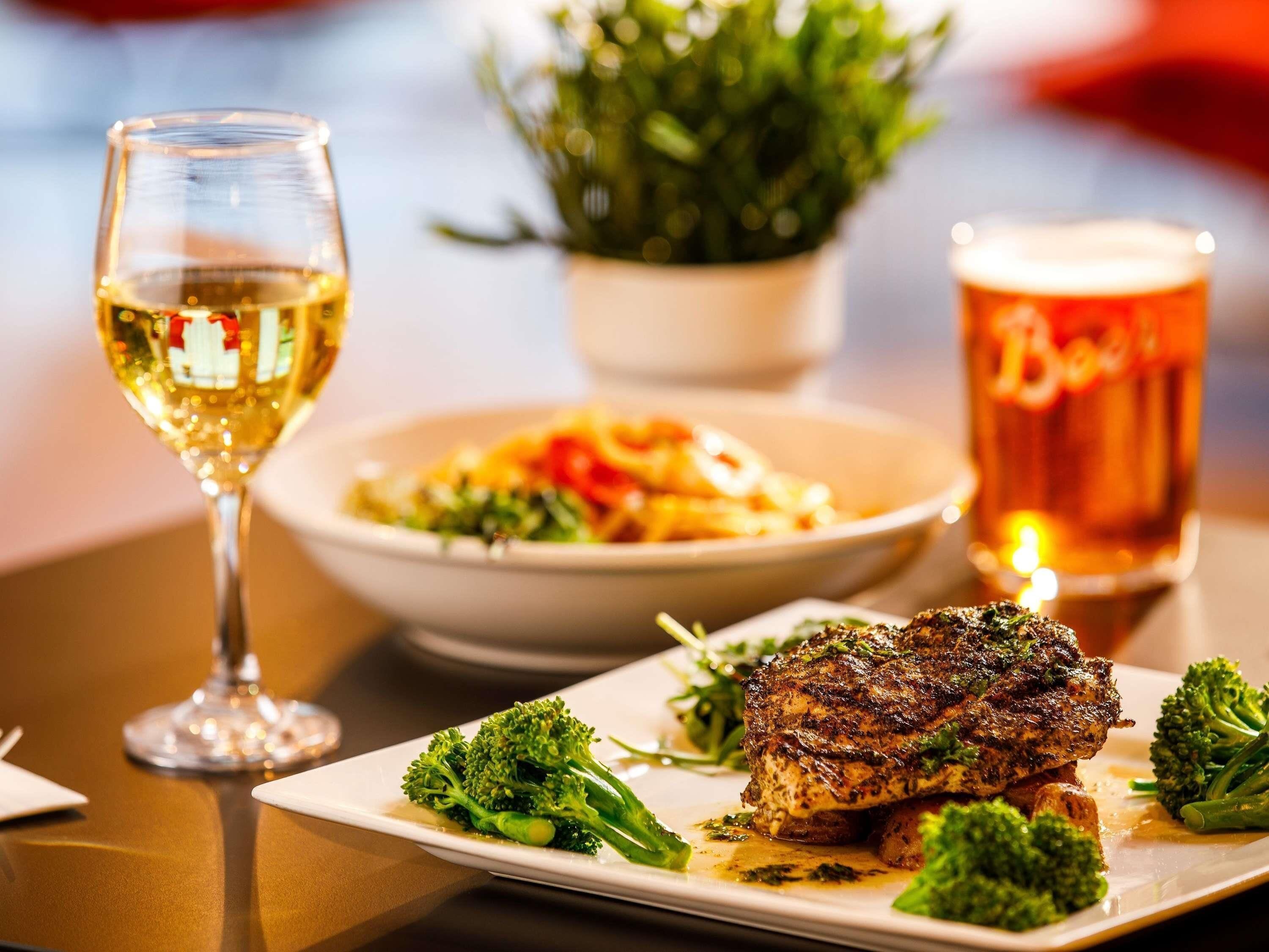 A dining table with a plate of food, a glass of wine, and a beer mug.