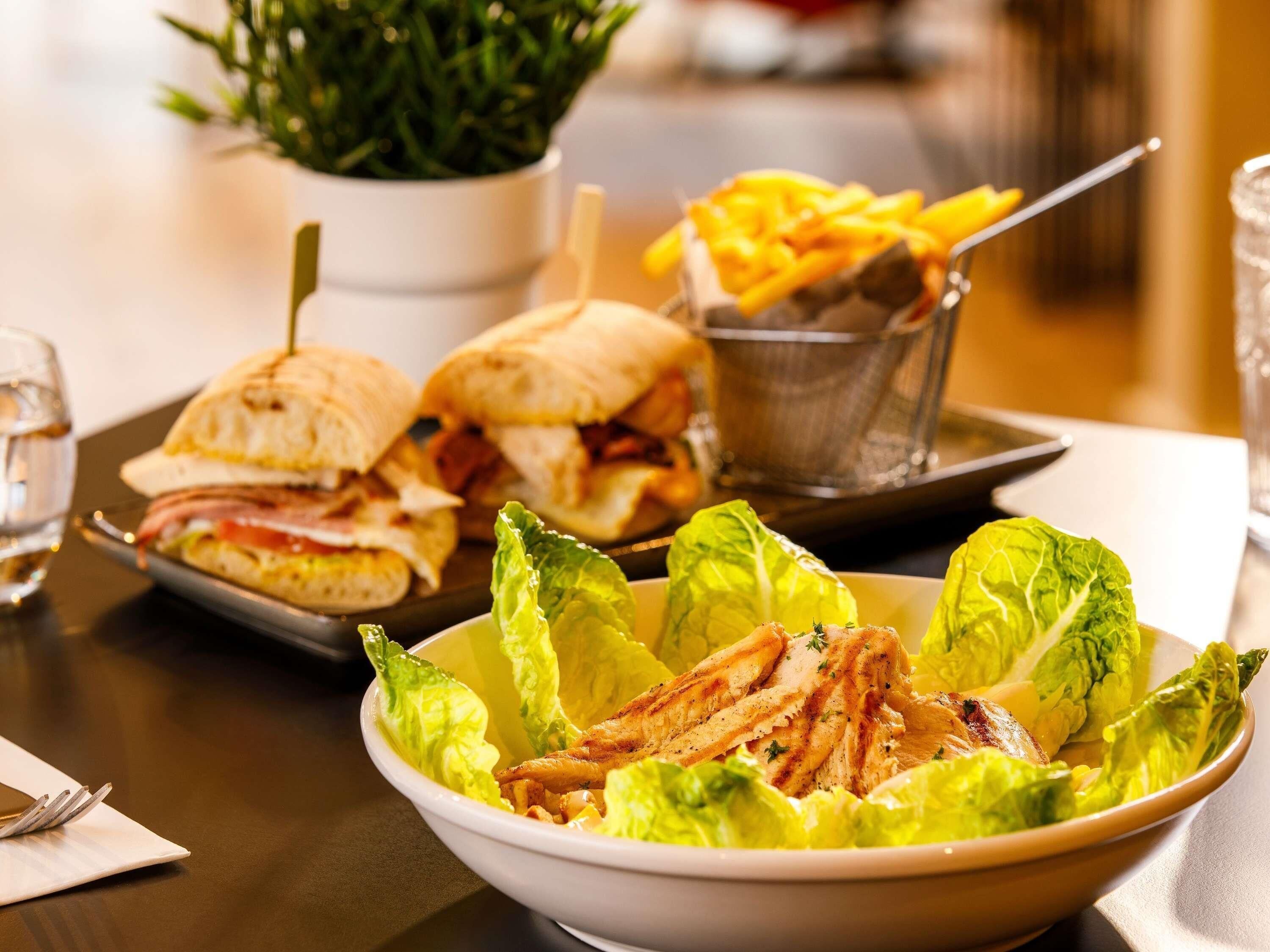 Un repas composé d’un sandwich, de frites et d’une salade avec de la laitue et du poulet.