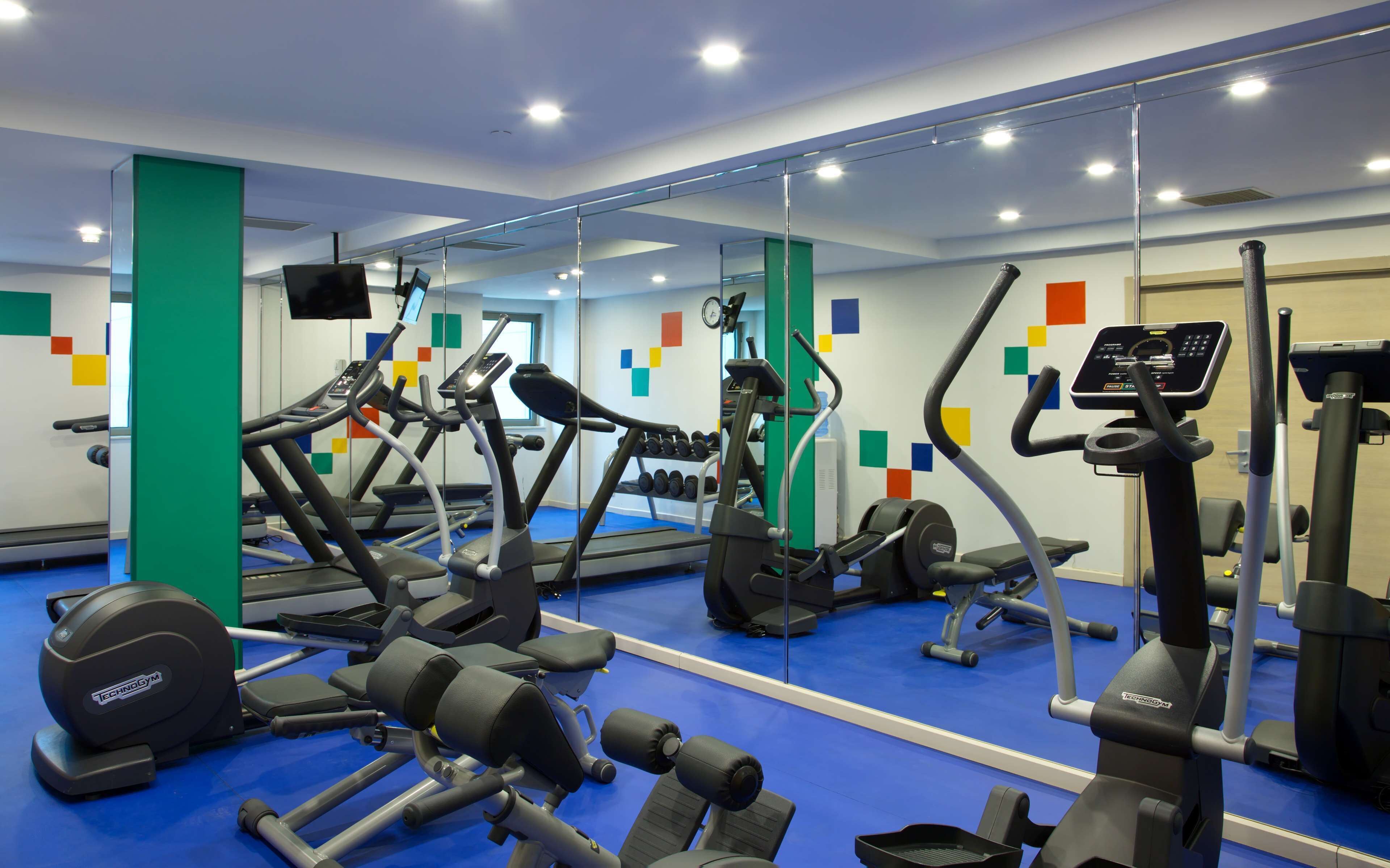 A modern gym with various exercise equipment, including treadmills, elliptical machines, and weight machines.