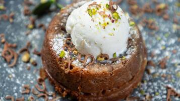 A dessert with a scoop of ice cream on top, garnished with nuts and sprinkled with powdered sugar.