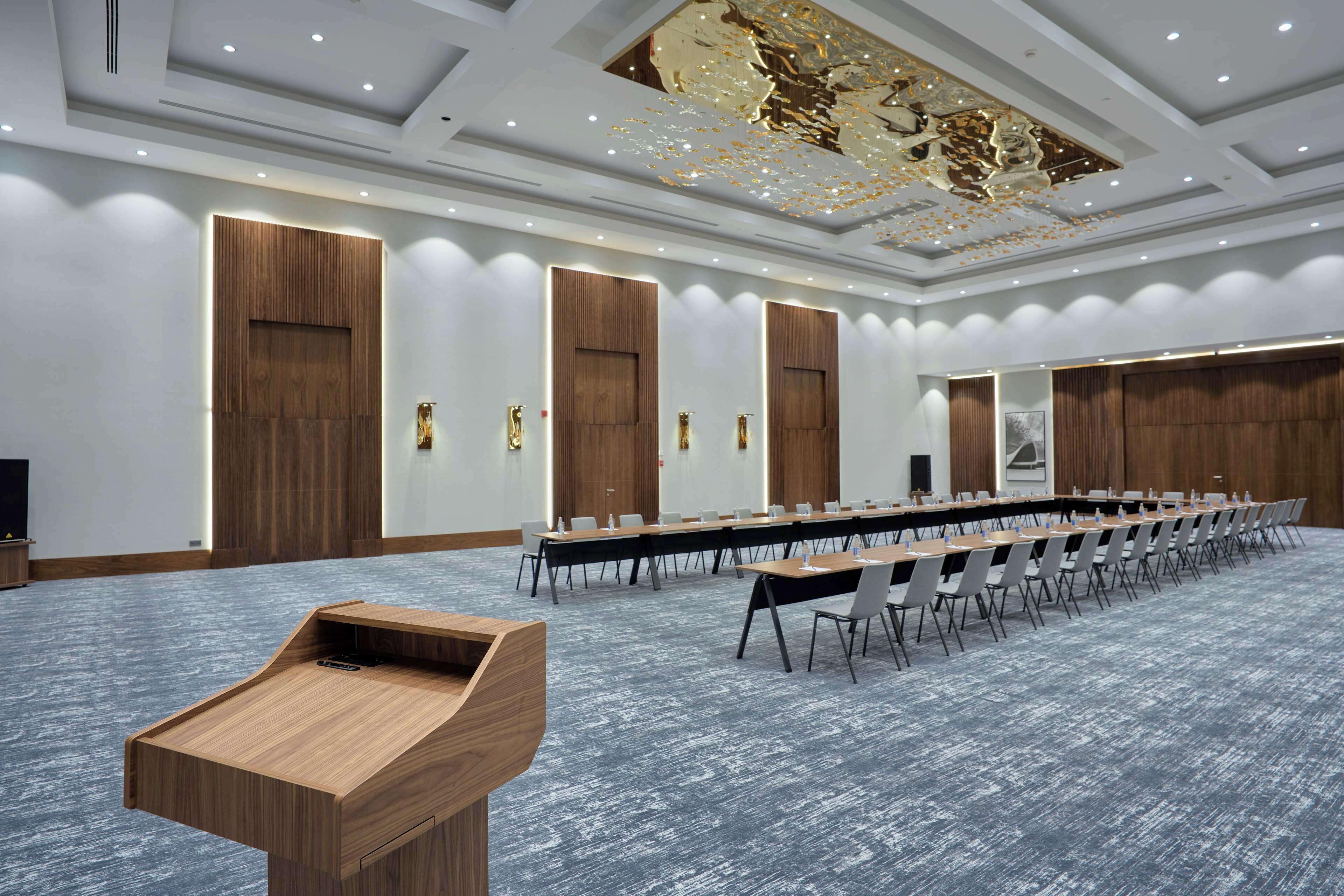 Una sala conferenze con un lungo tavolo, sedie e un podio.